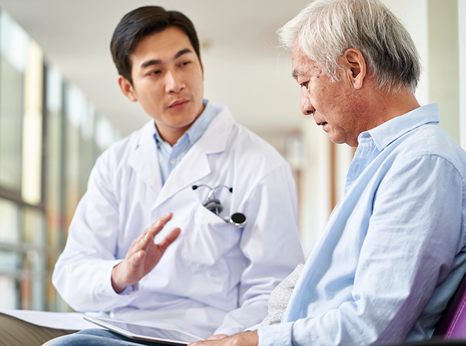 Doctor speaking with senior male patient in clinical setting, focusing on shared decision-making and personalized care planning in chronic disease management
