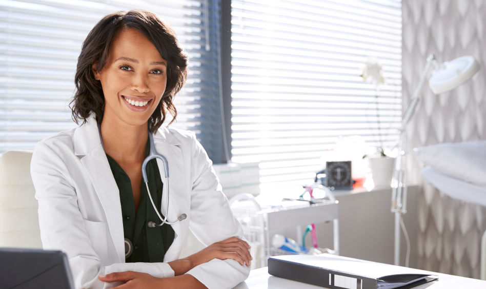 Smiling female provider in medical office with stethoscope, symbolizing compassionate and modern care delivery.