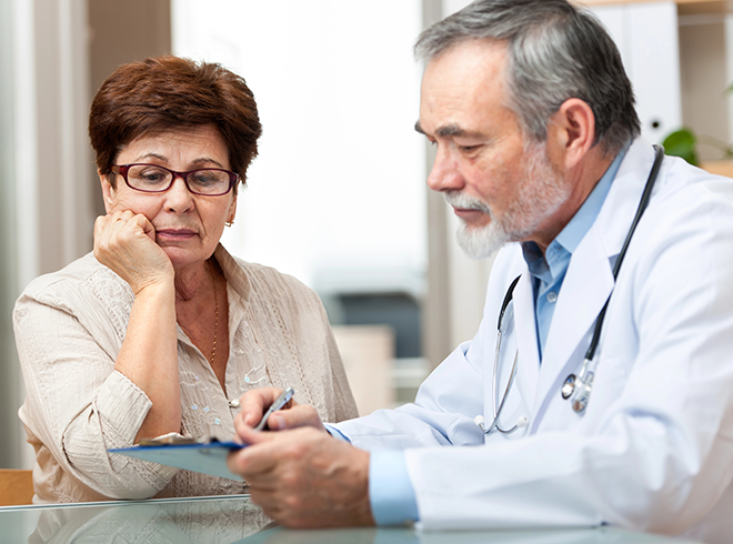 Senior woman reviewing care plan with male physician during medical consultation, illustrating shared decision-making and chronic condition management in primary care